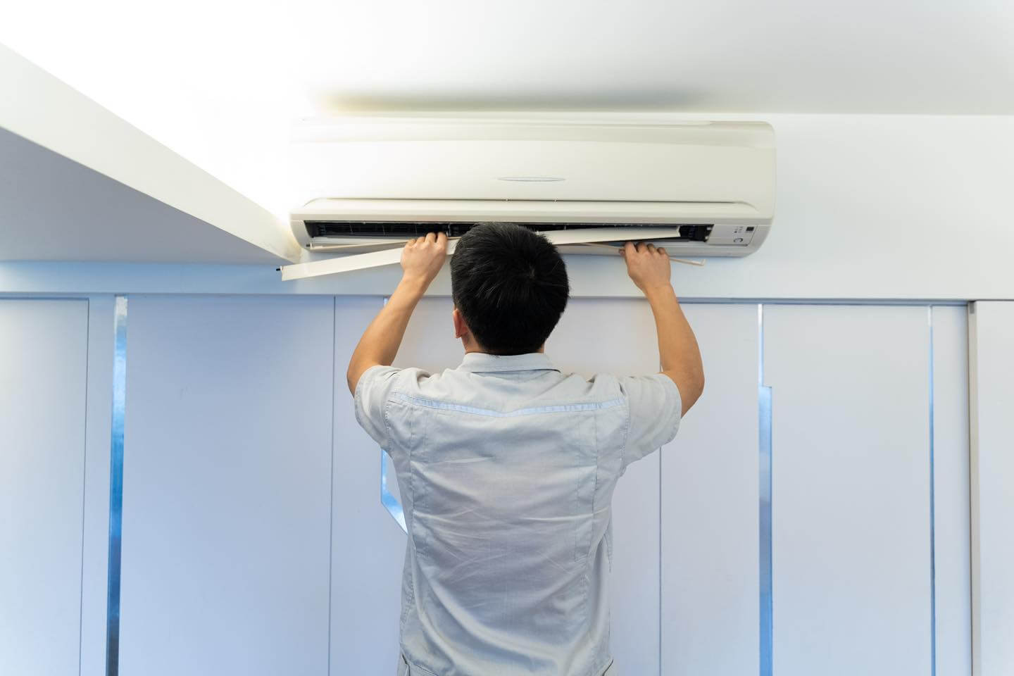 技師拆開冷氣面板進行保養清潔｜冷氣維修現場示意圖